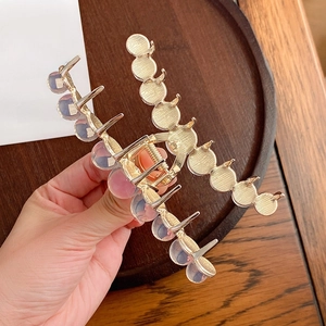 Elegant gold alloy shark hair claw clip featuring iridescent beads held in hand
