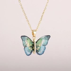 Macro detail of acrylic butterfly necklace featuring blue-green gradient and gold foil