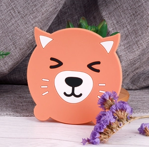 Detailed view of an orange silicone animal cartoon coaster on a light wood tabletop