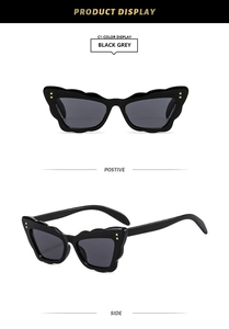 Front and side views of black cat-eye sunglasses with golden studs and grey lenses