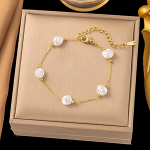Detailed macro view of a gold chain necklace with five baroque pearls on a silk background