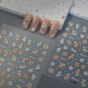 Detailed view of 3D relief floral nail stickers with orange flowers and crystals