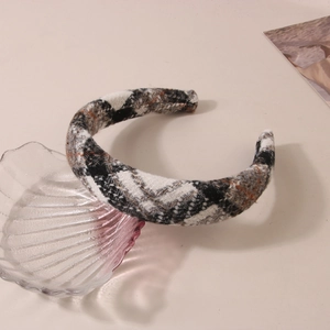 Close-up of thick checkered wool headband in black white and brown on a shell plate