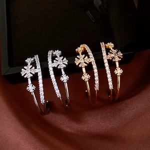 Detailed shot of gold and silver double-layer C-shaped earrings with zircon flowers