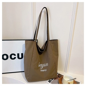 Detail showing the large olive green tote bag with beyou merci letter print and texture