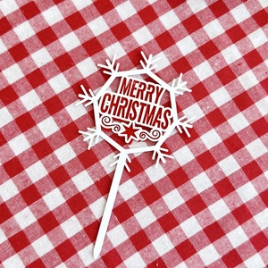 Close-up of red and white acrylic snowflake cake topper with Merry Christmas cutout