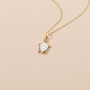 Detailed close-up of a turtle pendant with white enamel shell and gold chain link