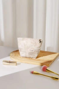 Détail de broderie florale sur trousse de maquillage crème avec zip en fleur