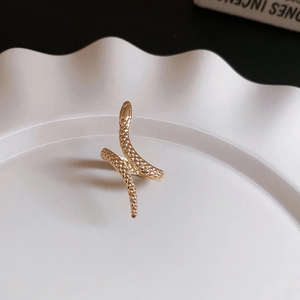 Detailed close-up of a gold snake-shaped ring on a white wavy display plate