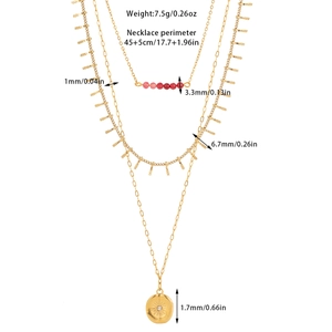 Detailed view of triple-layered gold-tone necklace with sunburst pendant and red beads
