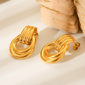 Macro detail of gold twisted hoop earrings with a polished finish on a stone background