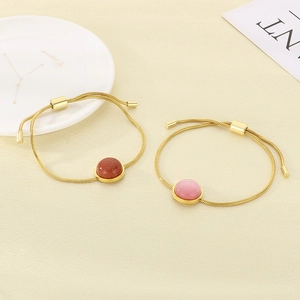 Détail de bracelets chaîne serpent dorés avec grès rouge et pierre œil de chat rose sertis