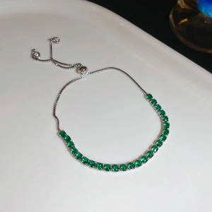 Detail of adjustable silver bolo bracelet featuring round cut emerald green cubic zirconia
