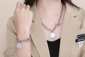 Silver chunky chain jewelry set with coin pendant worn over a beige blazer
