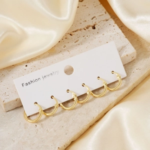Set of five gold circular geometric hoop earrings displayed on elegant white card paper