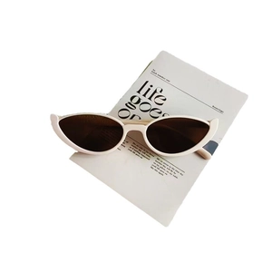 Modern white cat-eye sunglasses with dark brown lenses on a fashion magazine