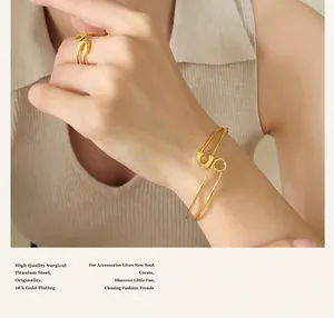 Close-up of 18k gold plated titanium steel safety pin bracelet and ring set on wrist