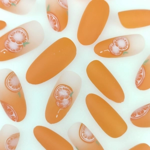 Long oval orange gradient press-on nails with matte finish and citrus patterns
