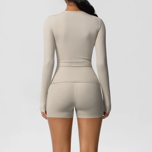 Detail view of the back seams on a beige long-sleeve yoga top and high-waist fitness shorts