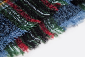 Detail shot of vintage plaid pattern and soft fringe tassels on a hooded poncho shawl