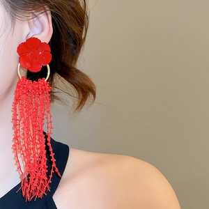Detail of red floral earrings featuring long beaded tassels and golden metal rings