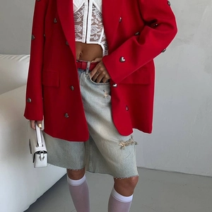 Detail of red oversized blazer paired with white lace top and denim skirt for street style