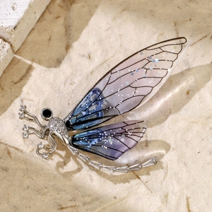 Macro detail of silver dragonfly brooch with blue purple gradient wings and black gems