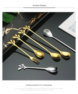 Close-up of stainless steel spoon and fork with leaf shaped handles on marble