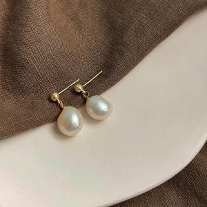 Macro detail of French vintage baroque pearl drop earrings with elegant gold metal finish