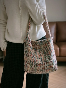 Close-up of a colorful woven knit tote bag with rich tweed texture and a long strap