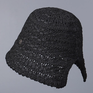 Detail of black crochet bucket hat showing hollow knit texture and metal side logo