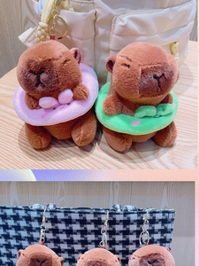Detailed close-up of plush capybara charms with colorful swim rings on a plaid bag