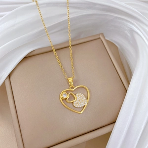 Detail of gold heart pendant with hollow design and inlaid cubic zirconia crystals