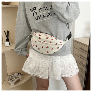 Detailed shot of a white corduroy crossbody bag featuring a cute red strawberry print