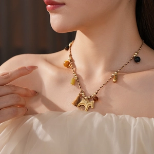 Close-up of woven horse pendant necklace with golden beads and tassel on neck