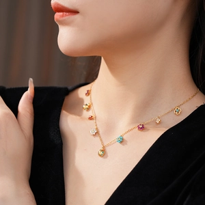 Detail of gold necklace with colorful enamel flower and ladybug pendants on neck