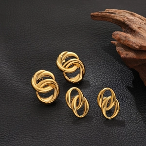 Close-up of interlocking 18K gold-plated oval and round hoop earrings on a black texture