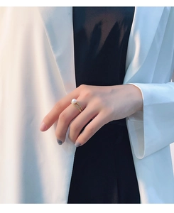 Detailed view of elegant double-layered gold ring with a single white pearl on a hand