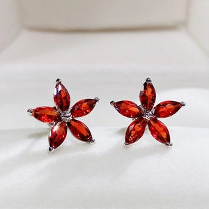 Macro view of flower stud earrings featuring five marquise-cut red gems in a silver claw setting