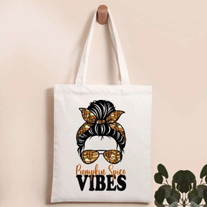 Detail of white canvas tote bag with Halloween pumpkin spice graphics on a wooden hook