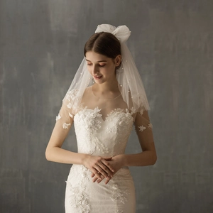 Short double-layer white bridal veil with pearl bow and elegant lace wedding dress details