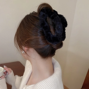 Close-up of a soft black plush faux fur scrunchie worn on a messy bun hairstyle