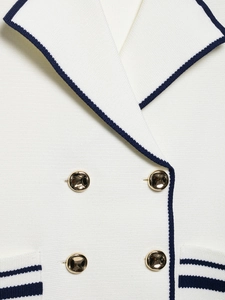 Close-up of cream knit blazer collar with navy trim and gold double-breasted buttons