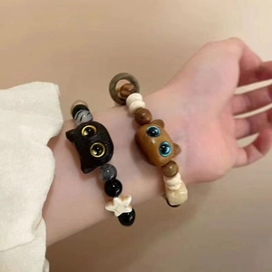 Close-up of cute cat-shaped beaded bracelets with wooden charms on a person's wrist