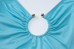 Dettaglio del vestito blu con drappeggio e decorazioni sferiche in metallo dorato
