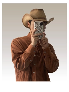 Detail of a brown woven western cowboy straw hat paired with a corduroy shirt