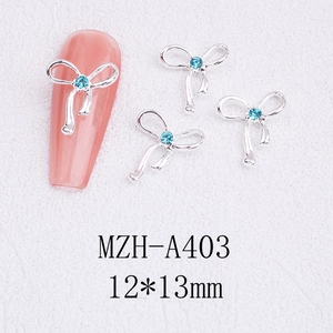 Macro detail of hollow silver bowknot nail art charms with blue rhinestone inlay