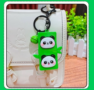 Detail of cute panda and green bamboo silicone keychain pendant on a white bag