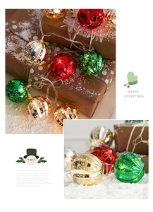 Close-up of LED Christmas light string with striped colorful balls on a gift box