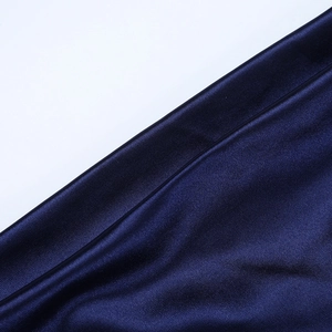 Détail macro du tissu en satin bleu marine montrant sa texture lisse et son éclat